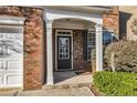 Close up of front entrance featuring storm door, white pillars, brick facade and manicured garden at 1538 Park Grove Dr, Lawrenceville, GA 30046