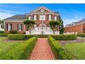 Elegant brick home with a manicured lawn, trimmed hedges, and a brick walkway leading to the entrance at 5070 Riverlake Dr, Peachtree Corners, GA 30097