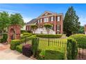 Beautiful two-story brick home with manicured landscaping, a wrought iron fence and a charming brick archway at 5070 Riverlake Dr, Peachtree Corners, GA 30097