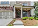 Close up of the home's entry, with brick facade, covered porch, and manicured landscaping at 919 Olmsted Ln, Johns Creek, GA 30097