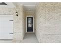 Close-up of the front door, flanked by brickwork and stylish outdoor lighting at 7760 Sheffield Ter, Fairburn, GA 30213