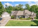 Charming home featuring a detached garage, lush lawn, and complemented by surrounding trees at 132 Copper Hills Dr, Canton, GA 30114