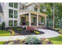 Inviting covered front porch featuring a brick base, white columns, and landscaped flower beds at 1084 Wrights Mill Rd, Canton, GA 30115