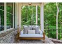Relaxing porch swing with comfortable cushions, perfect for enjoying the serene wooded surroundings at 1084 Wrights Mill Rd, Canton, GA 30115