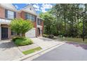 Exterior view of a brick townhome with a one-car garage, green lawn, and driveway at 5686 Lawley Dr, Alpharetta, GA 30022