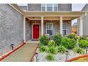Inviting front porch with a bright red door, lovely landscaping, and a cozy seating area at 5452 Fountainhead Ln, Auburn, GA 30011