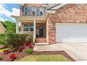 Inviting entrance of brick home with landscaped garden, covered porch, and black front door at 3845 New Salem Ct, Cumming, GA 30040