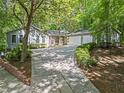 Exterior view of home with a long driveway leading to a three-car garage, surrounded by lush trees at 4700 Township Walk, Marietta, GA 30066
