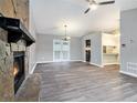 Open-concept living room featuring a stone fireplace, wood-look flooring, and access to the kitchen and backyard at 3918 S Creek Ct, Stone Mountain, GA 30083