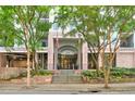 Exterior of the building's grand entrance featuring a brick facade, American flags, and mature trees at 275 13Th Ne St # 409, Atlanta, GA 30309