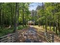 A beautiful long driveway leads up to a charming house surrounded by lush green trees at 48 Paschal St, Temple, GA 30179