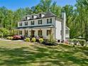 Beautifully landscaped yard surrounding this two-story home with a covered front porch and a glimpse of a backyard pool at 650 Jones Rd, Roswell, GA 30075