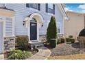 Close-up of a front door with stone accents, a curved walkway, and manicured shrubs in front of the house at 3750 Thackary Dr, Powder Springs, GA 30127