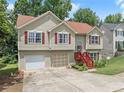 Lovely split-level home featuring a manicured lawn, a two-car garage, and mature trees at 1647 Tunbridge Ln, Lawrenceville, GA 30043