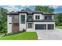 Striking two-story home boasts a modern exterior, multi-car garage, and lush landscaping at 165 Westbrook St, Buford, GA 30518