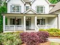 Charming front porch with white columns, gray shutters, glass door and colorful landscaping at 4910 Conover Dr, Atlanta, GA 30338