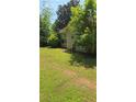 A tranquil backyard with lush greenery and a chair tucked beside the home's exterior at 65 King James Se Ct, Conyers, GA 30013