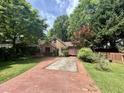 Quaint brick home with mature trees, a brick driveway, and lush landscaping at 725 Brown Pl, Decatur, GA 30030