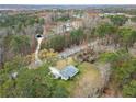 Aerial view of house surrounded by lush trees and a winding path to a detached garage or shed at 1892 Buford Dam Rd, Buford, GA 30518