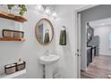 Stylish half bath with pedestal sink, oval mirror, and decorative floating shelves at 4658 Electric Sw Ave, Mableton, GA 30126