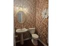 Stylish powder room with unique wallpaper and a pedestal sink at 3703 Liberty Sw Dr, Powder Springs, GA 30127