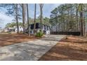 View of the home from the driveway with mature trees at 7020 Camp Valley Rd, Riverdale, GA 30296