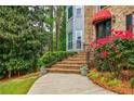 Close-up of the front entrance with brick steps, wrought iron railings, and lush landscaping with vibrant red flowers at 3389 Robinson Farms Ne Trce, Marietta, GA 30068