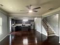 Open-concept living space with hardwood floors, gray walls, ceiling fan, staircase, and an adjacent kitchen at 2166 Villa Spring Ct, Dacula, GA 30019
