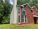 Angle of the brick house featuring large windows, partial siding and luscious green lawn at 6848 Timberhead Way, Lithonia, GA 30058