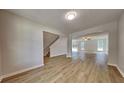 Open-concept living area with light colored vinyl flooring, staircase, and views to the backyard at 8256 Milam Loop, Fairburn, GA 30213