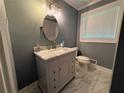 Bathroom with marble countertop vanity, oval mirror, updated lighting, and large window for plenty of natural light at 25 Stonehedge Dr, Buford, GA 30518