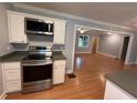 Kitchen boasts stainless steel appliances, white cabinets, and open layout to living area with beautiful hardwood flooring at 25 Stonehedge Dr, Buford, GA 30518