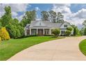 Charming home with a manicured lawn and a circular driveway, lush landscaping, and inviting entryway at 100 Ashley Hall Ct, Woodstock, GA 30188