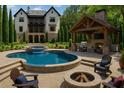Beautiful backyard retreat featuring a spacious pool, spa, outdoor kitchen and a cozy fire pit at 10765 Shallowford Rd, Roswell, GA 30075