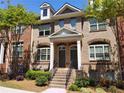 Charming townhome featuring a brick facade, dormer windows and landscaped front yard at 10856 Ellicot Way, Alpharetta, GA 30022