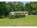 Charming single-story home with a lush green lawn and mature landscaping in a serene, wooded setting at 1824 Mcclung Rd, Hiram, GA 30141