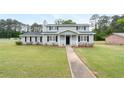 Inviting two-story home featuring a well-manicured lawn, mature trees, and charming architectural details at 100 Fairview Dr, Stockbridge, GA 30281