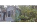 Side exterior view of home with peeling blue paint and overgrown trees at 1182 Bronx Nw St, Atlanta, GA 30314