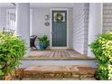 Inviting front porch with a green front door, classic columns, and stone steps at 6575 Eli Davis Rd, Cumming, GA 30040