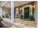 Inviting front porch featuring stone flooring, stacked stone, seating, a wreath and plenty of potted plants at 1495 Old Hunters Lake Dr, Marietta, GA 30062