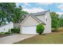 Side view of home with a two-car garage, vinyl siding, manicured lawn, and mature tree at 3230 Deer Valley Nw Dr, Acworth, GA 30101