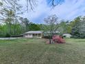 Well-maintained home with a green lawn and a small out-building surrounded by trees and flowering shrubs at 4445 Moon Station Nw Ln, Acworth, GA 30101
