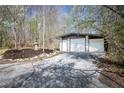 Detached three-car garage with white doors, surrounded by trees and a landscape rock garden at 5925 Old Bill Cook Rd, South Fulton, GA 30349