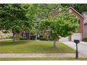 Traditional brick home with a lush green lawn, mature trees, and a two-car garage at 9744 Musket Ridge Cir, Jonesboro, GA 30238