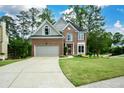 Charming brick home with lush lawn, beautiful landscaping, and a long driveway to the attached two-car garage at 2002 Fairbrook Ln, Woodstock, GA 30189