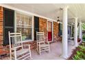 Inviting front porch featuring classic rocking chairs and a brick facade with black shutters at 2381 Woodacres Ne Rd, Atlanta, GA 30345
