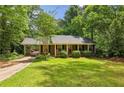 Quaint brick home with a lush green lawn and mature trees, complemented by a covered carport at 2381 Woodacres Rd, Atlanta, GA 30345