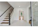 Bright entryway featuring tile floors, wooden stairs with black rails, and views into the adjacent living spaces at 51 Queen Anne Se Dr, Mableton, GA 30126
