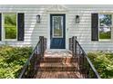 Inviting entrance with a navy blue front door, brick steps, manicured hedges, and stylish lighting fixtures at 51 Queen Anne Se Dr, Mableton, GA 30126
