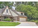 Tudor-style home featuring a brick facade, attached two-car garage and lush green landscaping at 12 Westchester Square Sq, Decatur, GA 30030